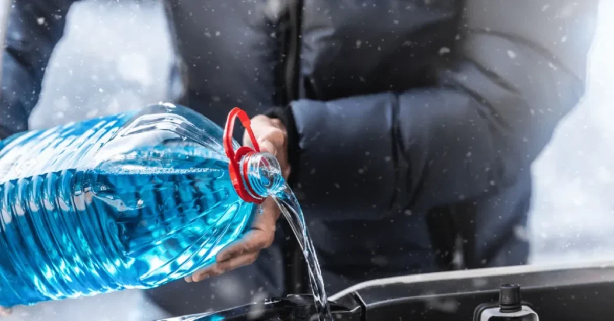 man pouring antifreeze into a car