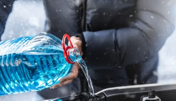 man pouring antifreeze into a car